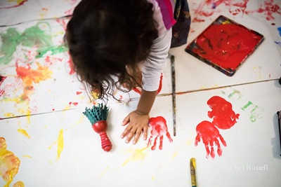 Birds-eye view of child making hand prints with paint.