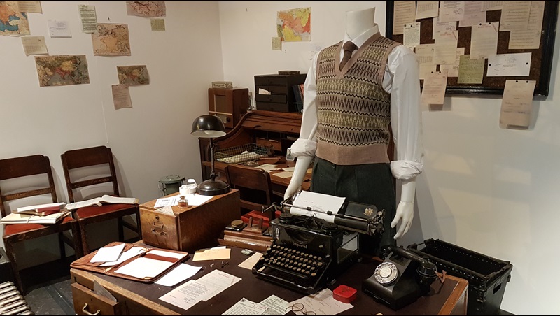 Alan Turing’s office at Bletchley Park, a desk with papers and a type writer on it. And a mannequin with a shirt and tie and sleeveless jumper.