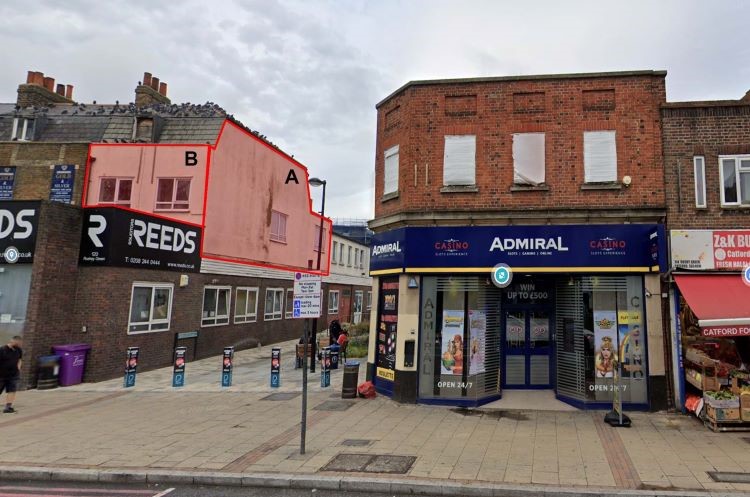 Shops on a high street. One shop name is Reeds, the other says Admiral and there's an alleyway between them. There is a red overlay printed on the section of building above the ship which has A and B on it
