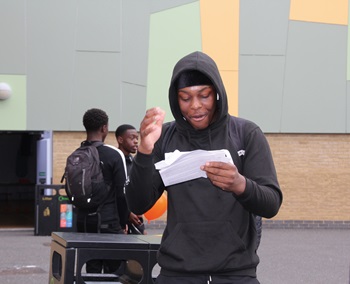 Young man opening his GCSE results at school and looking excited