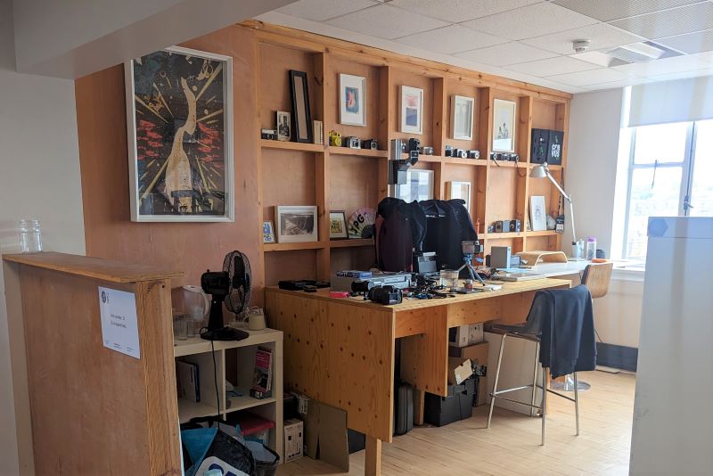 A workspace with desk, chair, lots of framed prints and a sewing machine