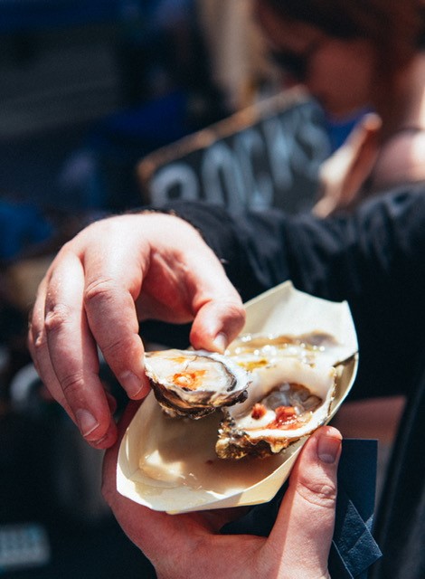 A pair of hands holding some shucked oysters. You can just about make out a blackboard behind with the word 'rocks' on it