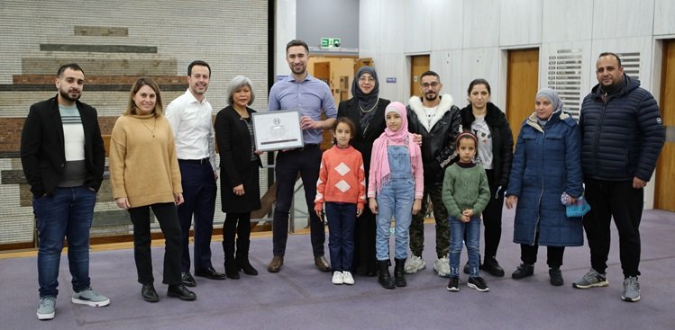 image of the mayor awarding an award with a refugee family