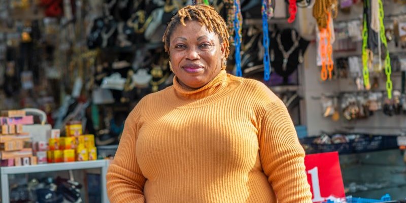 A black female business owner standing in front of her business, a shop which sells accessories 