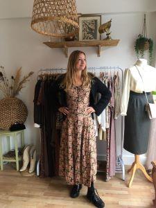 Celena Fernandez standing in her shop, Ansa Vintage. There are clothes behind her and a mannequin next to her