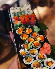 Maki rolls with a variety of fillings on a black plastic tray