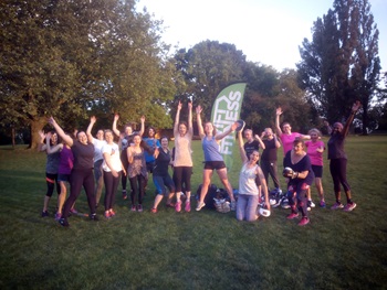 A large group of people cheering outside in the park after working out