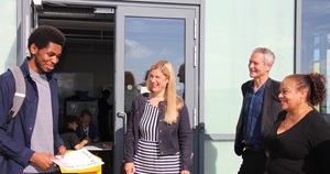 Councillors standing smiling with a young man holding his results with a smile. His results say A*, A, A, B.