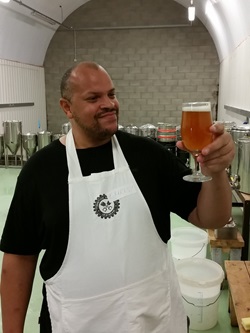 An Ignition Brewery employee holding up a glass of beer and looking at it.