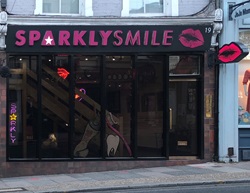 The outside of Sparkly Smile dentist. The sign is bold and pink. 