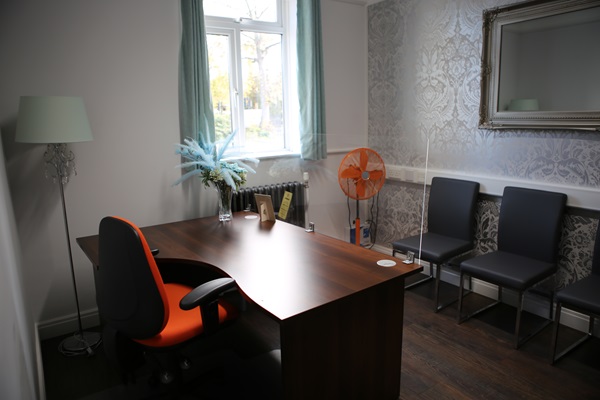 A room with an orange chair facing 2 chairs on the wall