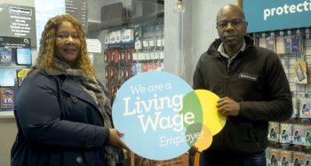 A man and woman holding a We Are a Living Wage Employer sign