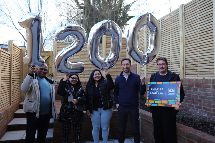 Damien Egan with residents in a garden. They are holding balloons that spell out 1200.