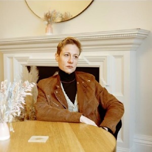 A woman in a brown jacket looks away from the camera