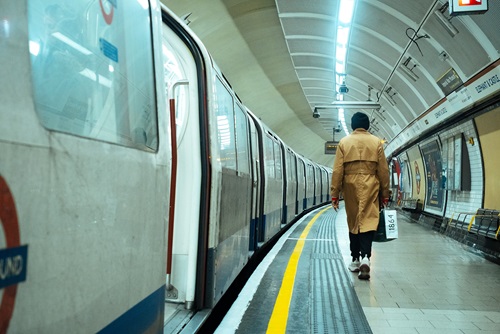 Bakerloo line TFL station with a train pulled into the station while a woman walks along the platform