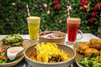A selection of fritter, salads and freshly squeezed juices laid out on a table