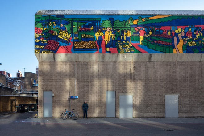 Gaurab stands below vibrant painting of Lewisham Market