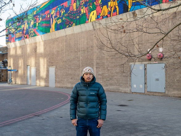 Gurab standing in front of his mural 'Lewisham'