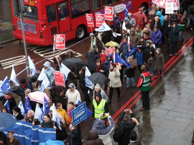 Protesters walking through street carrying placards and flags
