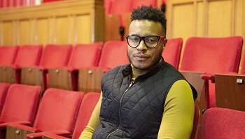 Cllr Andre Bourne sitting in the empty auditorium of The Broadway Theatre surrounded by empty red seats