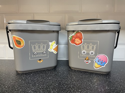 Two food waste caddies with fun stickers on them that look like a face