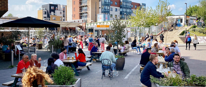 A street in Lewisham showing people eating at tables