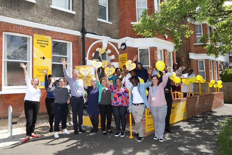 A group of people cheer and hold up yellow signs that say Foster for Lewisham