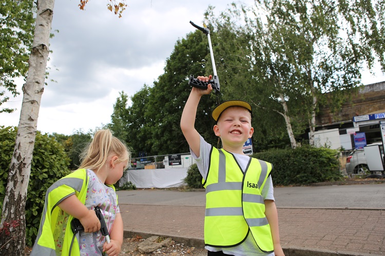 Isaac in his high-vis jacket, holding up a litter picker