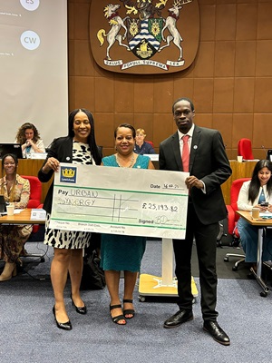 Two people stand with mayor Dacres holding a giant cheque 