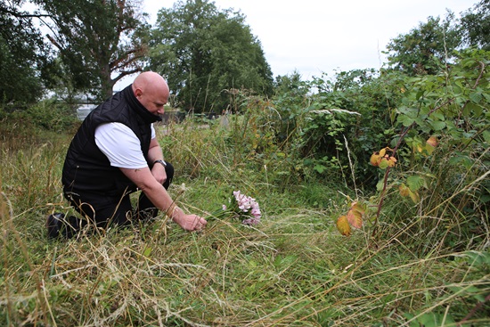 Colin Burgess, Head of Bereavement Services at Lewisham council, laying down flowers where on the location of one of the graves, where the memorial will be placed.